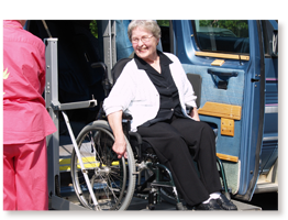 older woman in wheelchair coming out of lift van